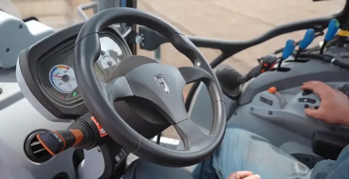 A farmer inside a tractor cab using the FJD AT2 Auto Steer System for hands-free steering.
