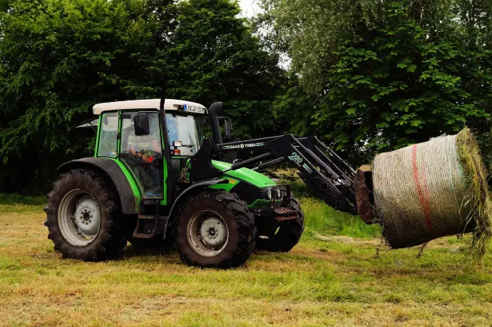 Small farm tractor with front-end loader handling heavy loads