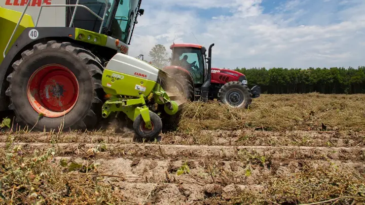 Tractor and baler working fields in spring farming and preparation