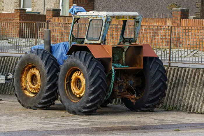 Rusty double-wheeled tractor near brick wall