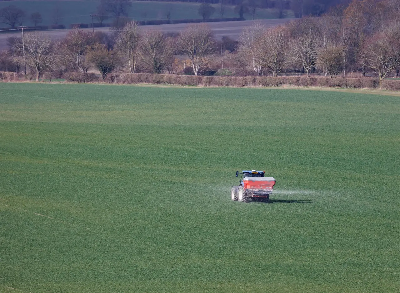 Precision agriculture in practice: A red tractor efficiently applies crop treatments across a healthy green field, demonstrating effective and targeted farm management amidst a serene rural environment.
